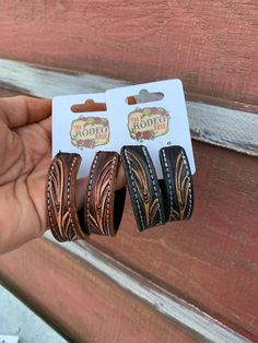 a person holding three pairs of brown and black hair clips in front of a wooden door