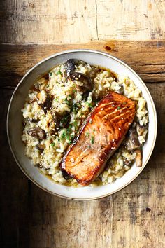 salmon and mushroom riso with rice in a bowl on a wooden table next to a fork