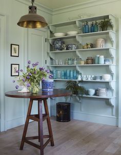 a wooden table sitting in front of a shelf filled with vases and bowls on top of it