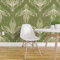 two white chairs sitting at a table in front of a wall with green leaves on it