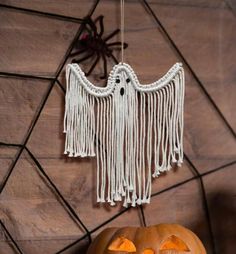 a carved pumpkin sitting on top of a wooden table next to a white string ghost