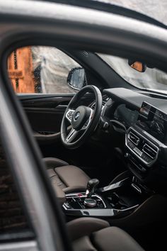 the interior of a car with leather seats and steering wheel, in front of a brick wall