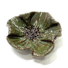 a green flower shaped dish sitting on top of a white table