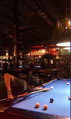 a man laying on top of a pool table