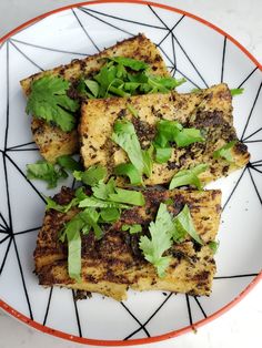 four pieces of tofu on a white plate with green leafy garnish