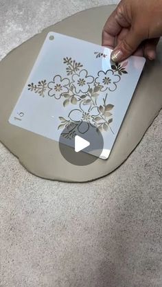 someone is using a cutting board to cut out flowers on the floor with their fingers