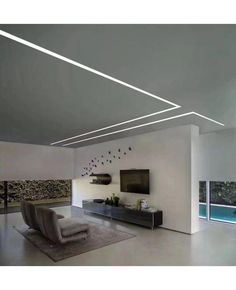 a modern living room with white walls and flooring is pictured in this image, the ceiling lights shine brightly