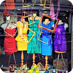 there are many dresses and shoes on display in the store front window, all different colors