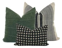 three pillows with different patterns on them, one black and the other green are sitting next to each other