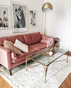 a living room with pink couches and pictures on the wall above it, along with a glass coffee table