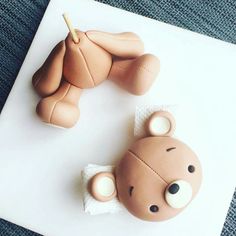 two teddy bears made out of fondant sitting on top of a white board with a pencil in their mouth