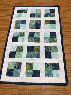 a close up of a quilt on a wooden floor with a table topper in the background