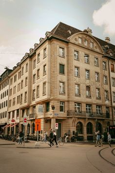 people walking on the street in front of a large building with many windows and balconies