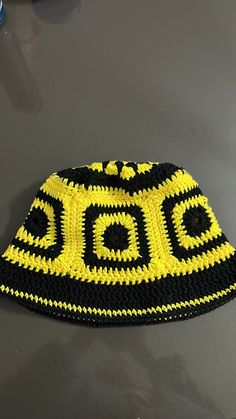 a crocheted black and yellow hat sitting on top of a gray countertop