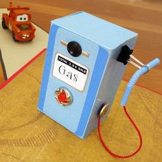 a blue and red gas pump sitting on top of a wooden table next to toy cars