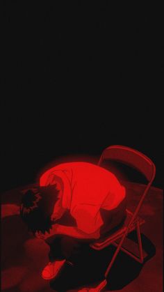 a red chair sitting on top of a wooden floor next to a person laying down