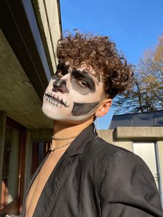 a man with his face painted to look like a skeleton is standing in front of a house