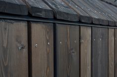 the side of a wooden building with metal studs on it's sides and wood slats