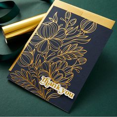 a close up of a greeting card on a green surface with gold foil and ribbon