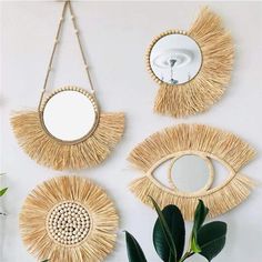 three mirrors hanging on the wall next to a potted plant and a mirror with an eye