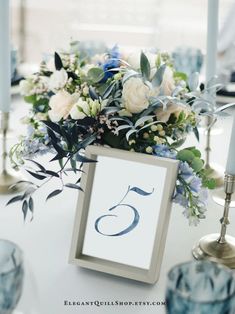 the table is set with candles, flowers and an elegant monogrammed centerpiece