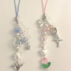 two necklaces with charms attached to them on a white surface, one is pink and the other is blue