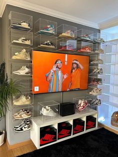 a large television mounted to the side of a wall with shoes on display in front of it