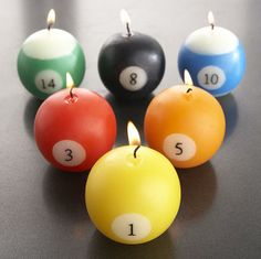 four pool balls with numbers on them sitting next to each other in front of candles