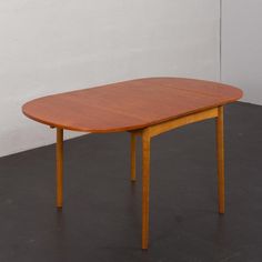 a wooden table sitting on top of a floor next to a white wall and black floor