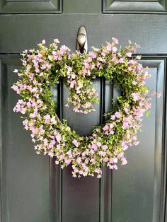 a wreath with pink flowers hanging on the front door to decorate it for someone's special occasion