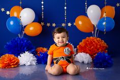 a little boy sitting on the floor in front of balloons