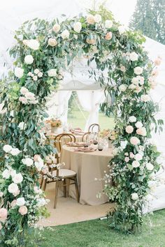 an outdoor table set up with flowers and greenery