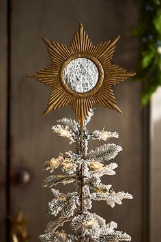 a white christmas tree with a gold star on top and snow flakes around it