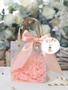 a pink bag with a bow on it and some gold straws next to it