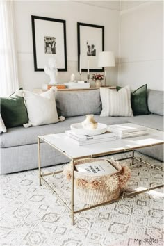 a living room with a couch, coffee table and pictures on the wall above it