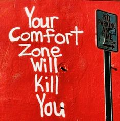 graffiti spray painted on the side of a red building reads your comfort zone will kill you