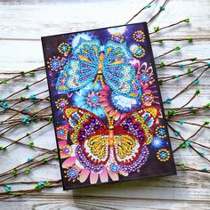 a card with colorful butterflies on it sitting next to some twigs and flowers in the background