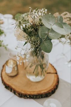 a vase filled with white flowers sitting on top of a wooden table next to candles