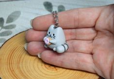 a hand holding a tiny keychain with a cat on it