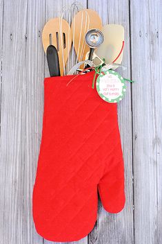 a red oven mitt with utensils in it on a wooden table top