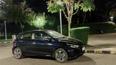 a black car is parked on the street at night