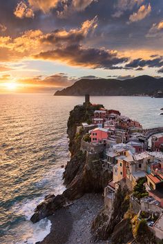 an aerial view of a village on the edge of a body of water at sunset