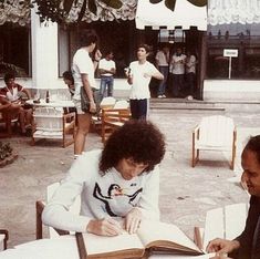 two men sitting at a table with an open book