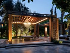 an outdoor dining area is lit up at night with lights on the ceiling and table in the center