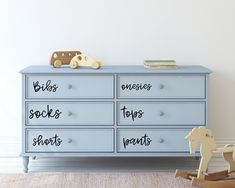 a blue dresser with writing on it and a rocking horse next to it in a white room