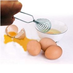 an egg being whisked into a bowl with eggs on the side and in front of it