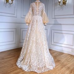 a dress on display in a room with white walls and wood flooring, along with chandeliers