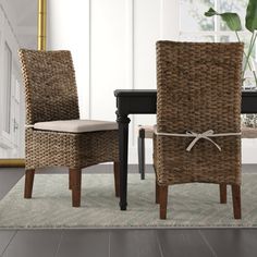 two wicker chairs tied to a table with a potted plant in the background