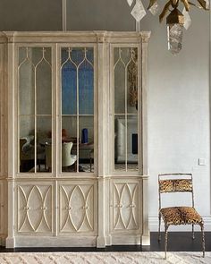 a white china cabinet sitting in the middle of a living room next to a leopard print chair