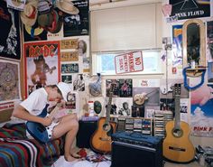 a man sitting on top of a bed next to a guitar